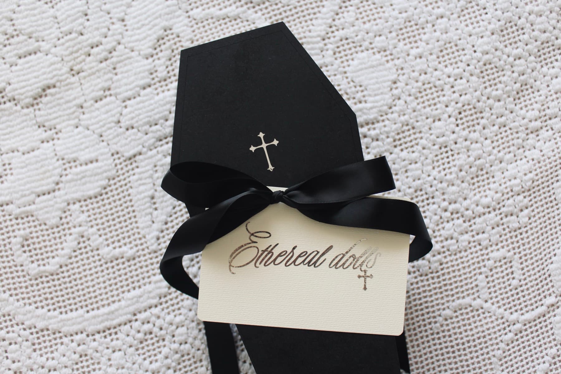 A black coffin box tied with a satin ribbon and an Ethereal Dolls card